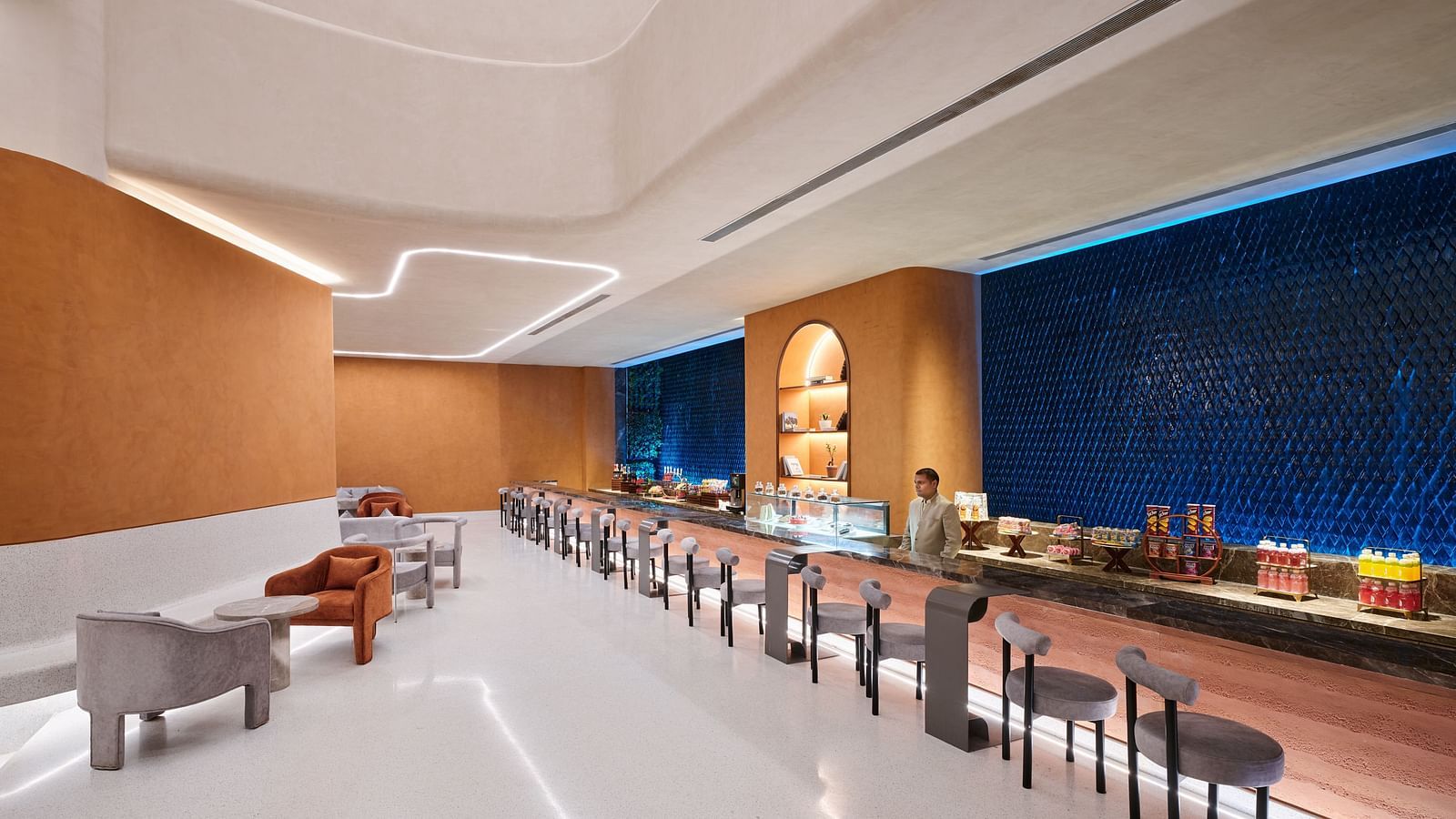 Image of Bean Hive restaurant with chairs arranged next to a running table and a bartender standing on the other side of the table
