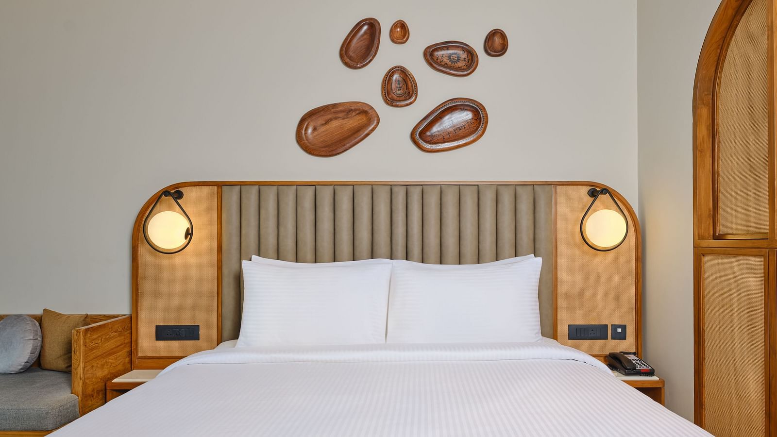 Image featuring a plush bed with pillows and warm lights on both sides and wall hangings on the wall