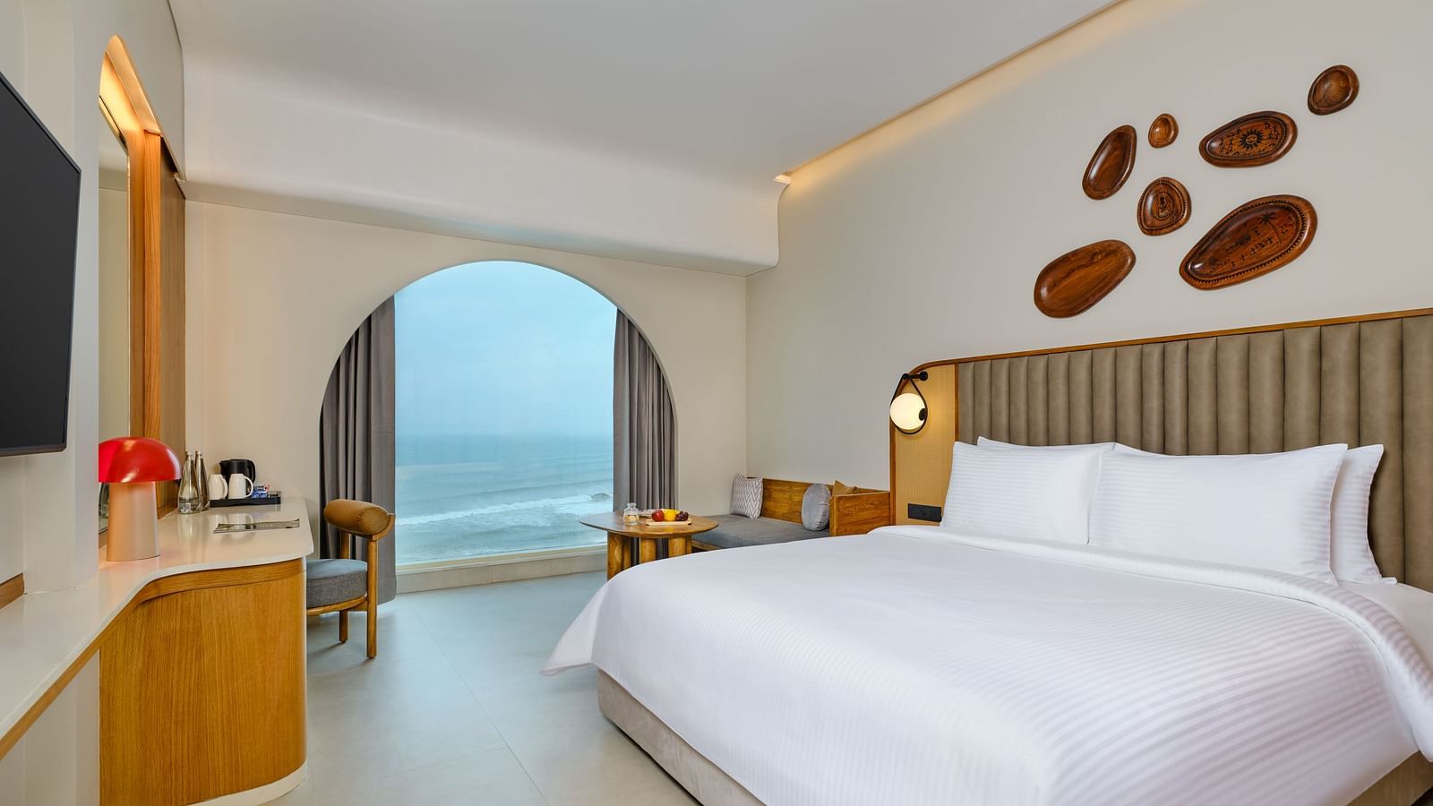 Image of the Sea View Room at Swosti Premium Beach Resorts in Puri featuring a plush bed and a TV next to which a work desk is placed beside the huge window with sea view