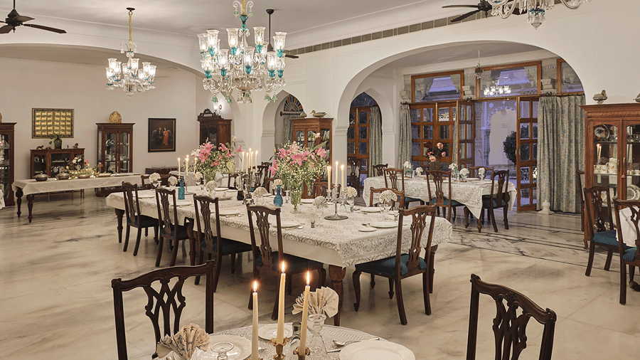 Formal dining hall with chandeliers and a long table set for a meal at Dev Shree, Deogarh.