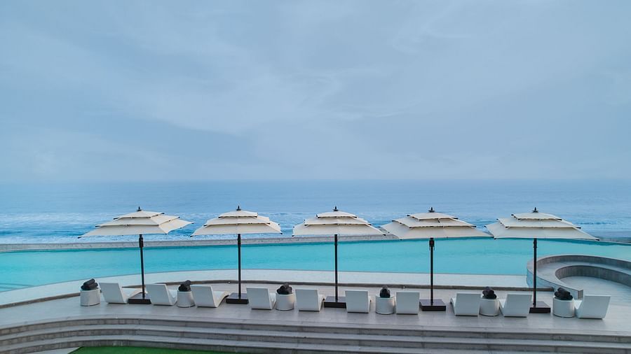 Swimming Pool at Swosti Premium Beach Resorts in Puri under a cloudy sky featuring pool deck and an infinite view of the sea appearing to be almost blended with the sky