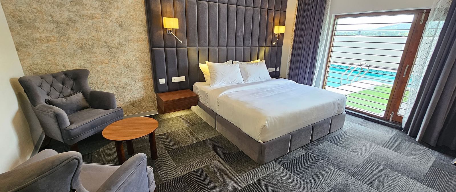 full view image of the premium room at Eminence The Corbett withe a comfortable double bed and huge windows besides it