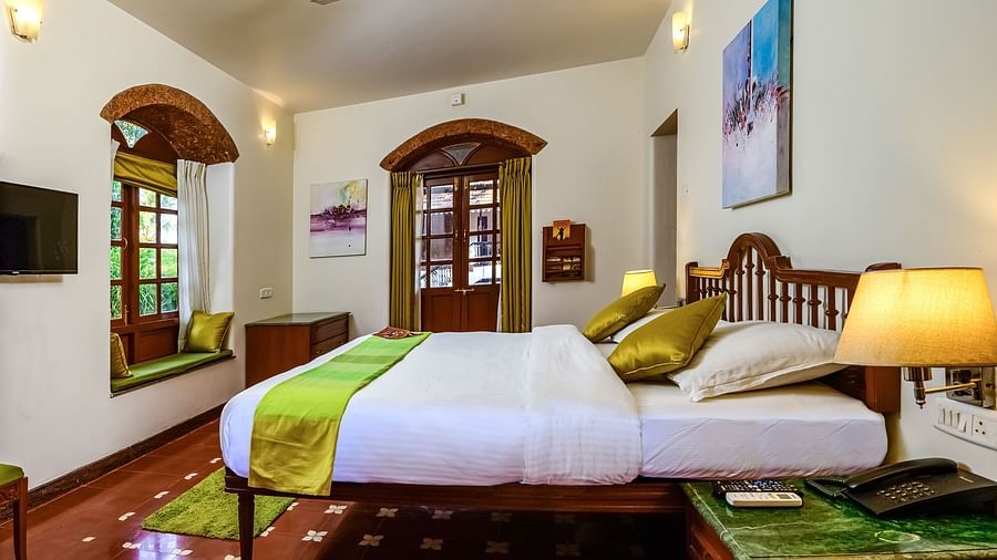 A double bed with a painting hung above marble side table inside Telina - River / Forest View room at neemrana s three waters