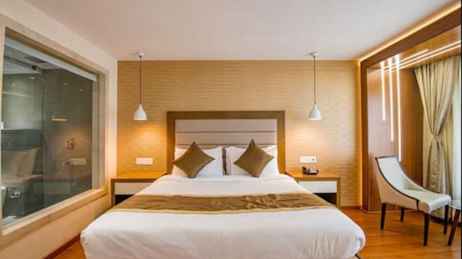 A spacious hotel room with a large bed, elegant seating area by the window, and tasteful lighting, creating a relaxing ambience.