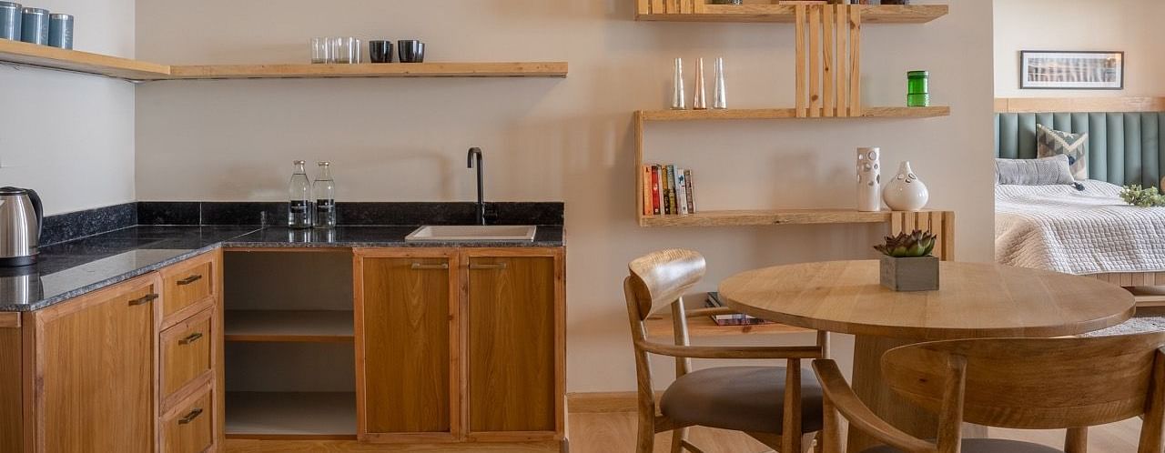 An image of kitchen space with dining table, cabinets and drawers, cupboards, utensil rack, etc. | Avalon Cottages, Kanatal