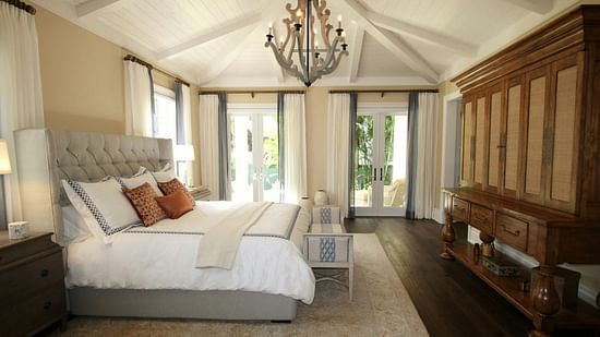 Side view image of the bed with a chandelier hanging over the double bed.