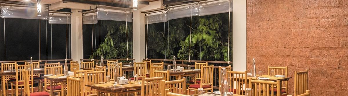The spacious indoor dining area at Forest Escapes Koyna offers ample seating under bright lighting.