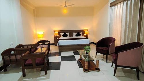 Executive Room at Pride Resort Rudraprayag featuring a double bed with lamps on both sides and sitting space in front of it 