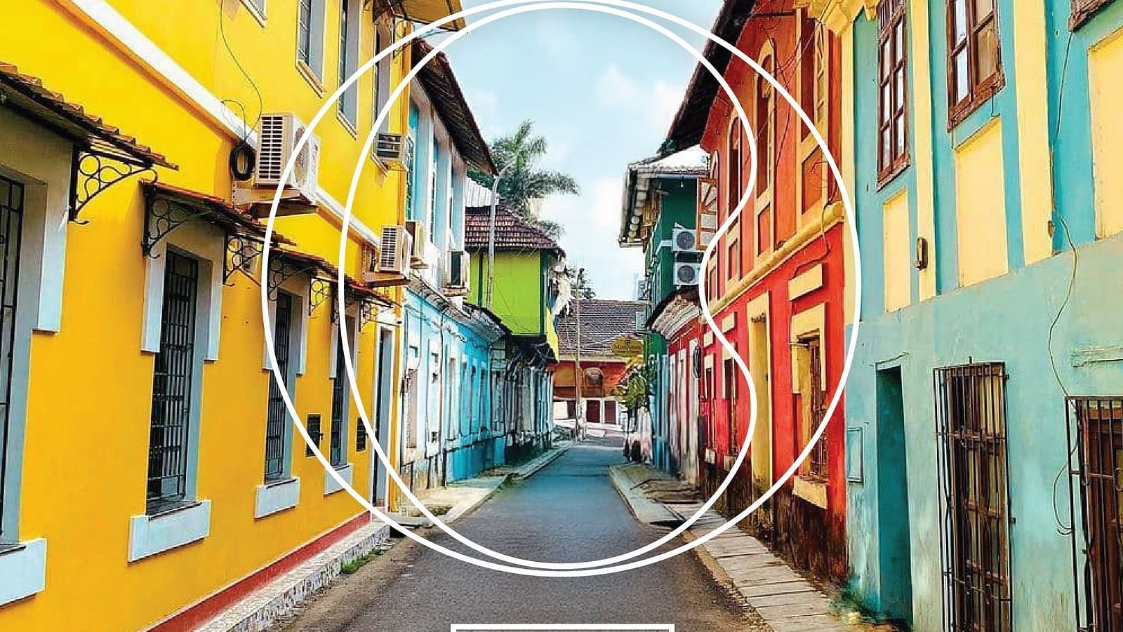 A wide angle shot of an alley in Goa with vibrant coloured buildings during a bright sunny day.