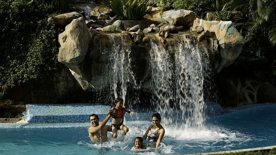 A family of four relaxing in a pool under a man made fountain - The Retreat Hotel and Convention Centre