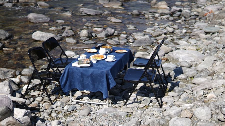 A breakfast table placed right besides a stream of water during the day