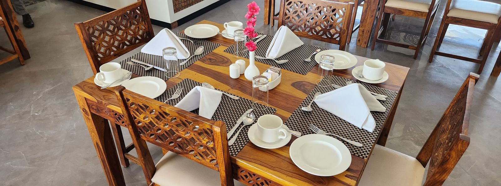 An indoor dining table set with plates and cutlery, ready for a meal at the Bamboo Saa Mulberry Resort, Pushkar.