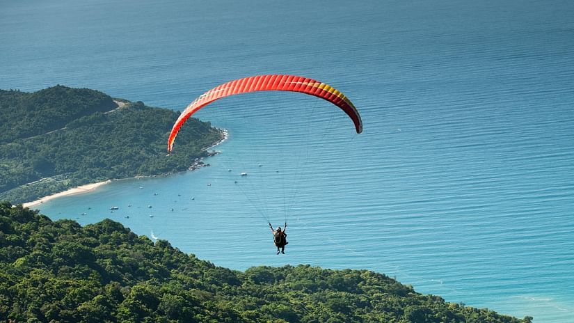 Photo of Person Paragliding Over Forest
