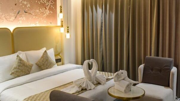 Side view of the king bed, sofas and table in between them inside the suite at Tulip Inn, Shravasti