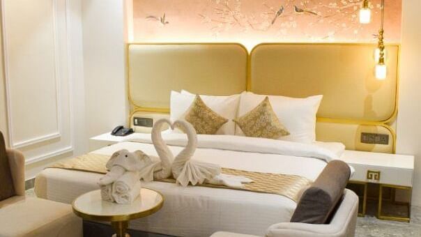 Side view of the king bed with sofas opposite it inside the suite at Tulip Inn, Shravasti