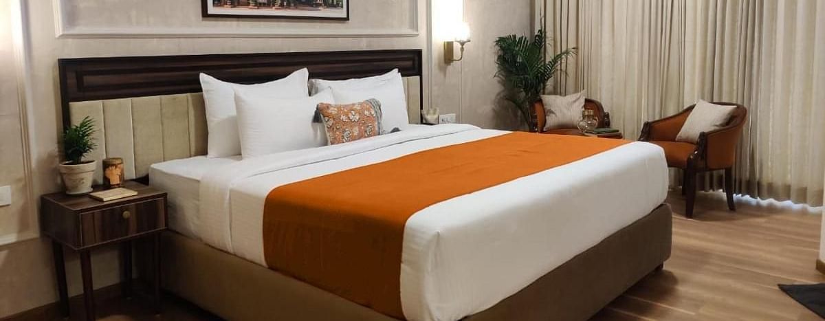 A well-lit Luxury King Room at Nalapad Hotel Bangalore International with a neatly made bed.