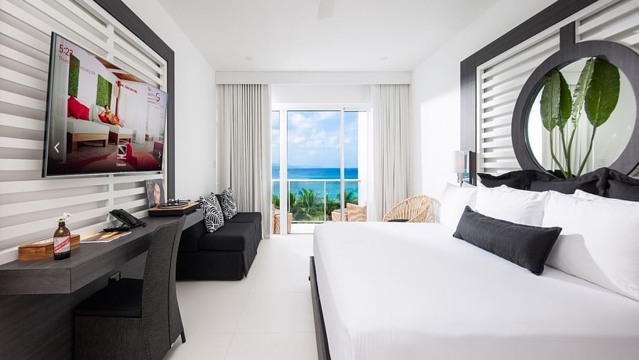 A view of our room offering a large bed, a wall-mounted television, and sea view - S Hotel Montego Bay, Jamaica