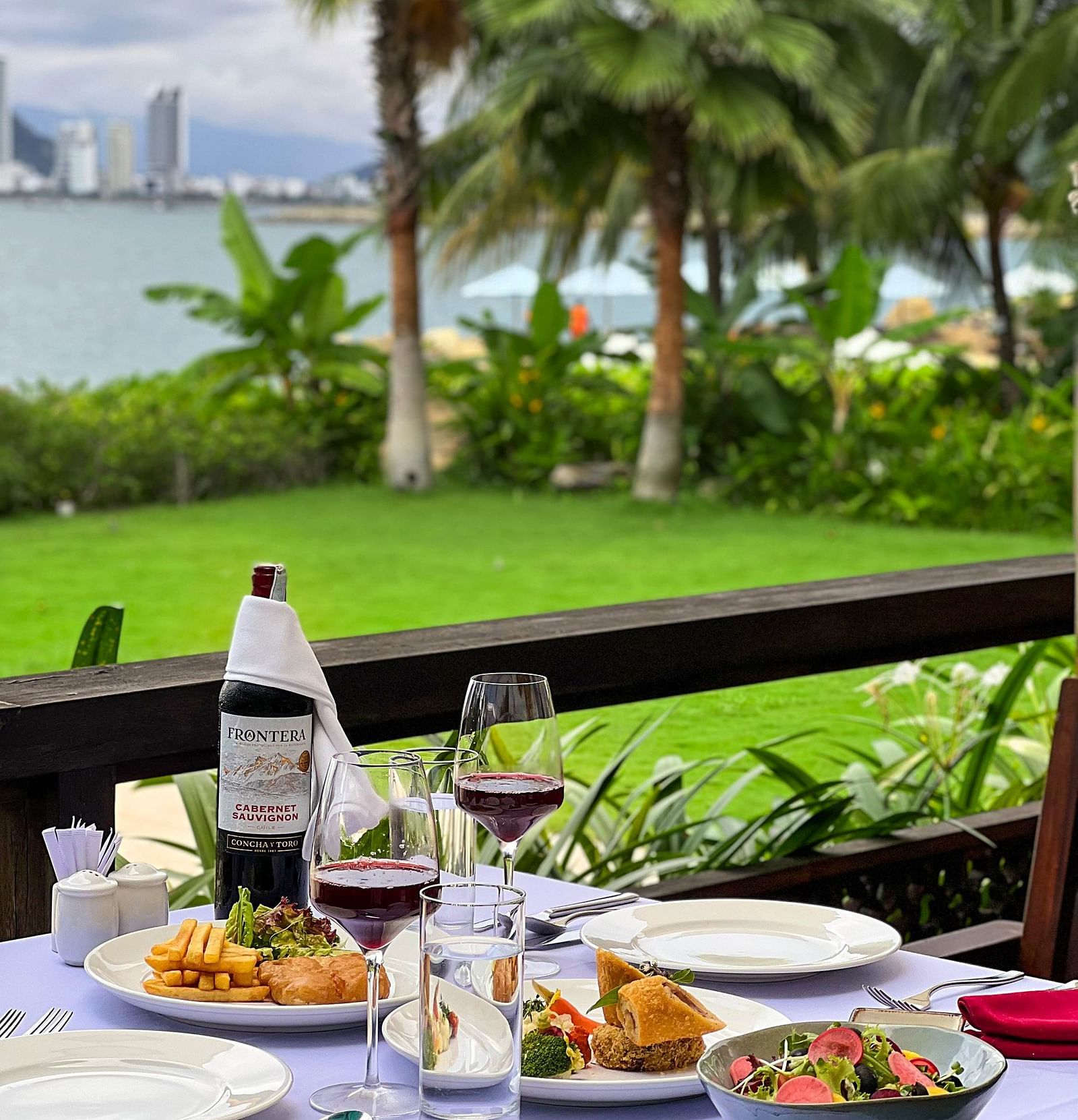 A table placed on the outdoor which has eatables placed - Alibu Resort Nha Thrang