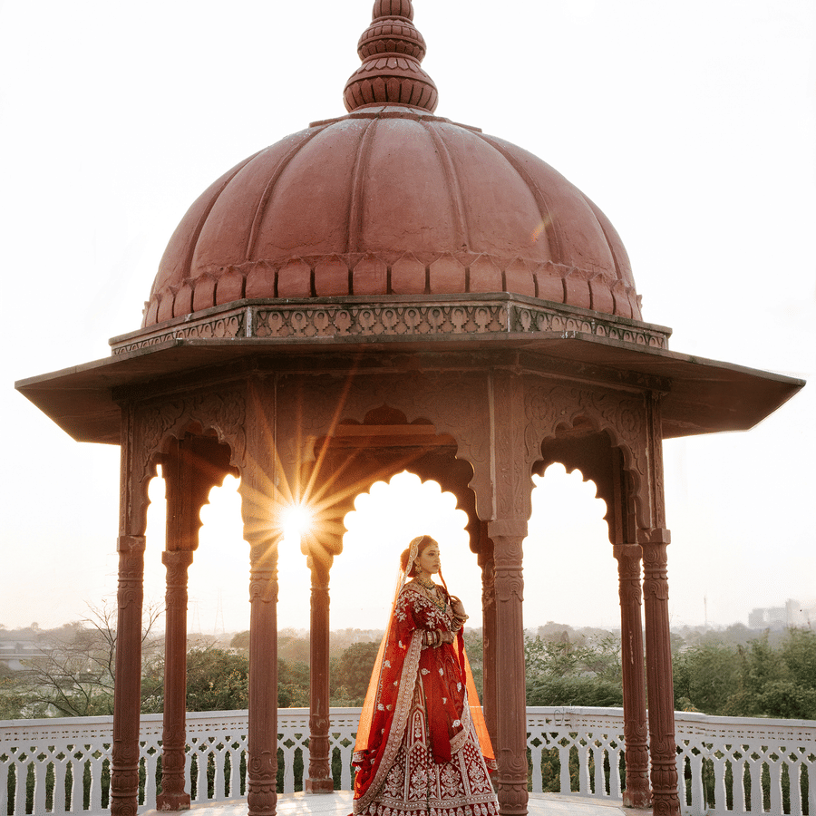 Bride standing under ornate heritage arches at Umaid Palace during golden hour.