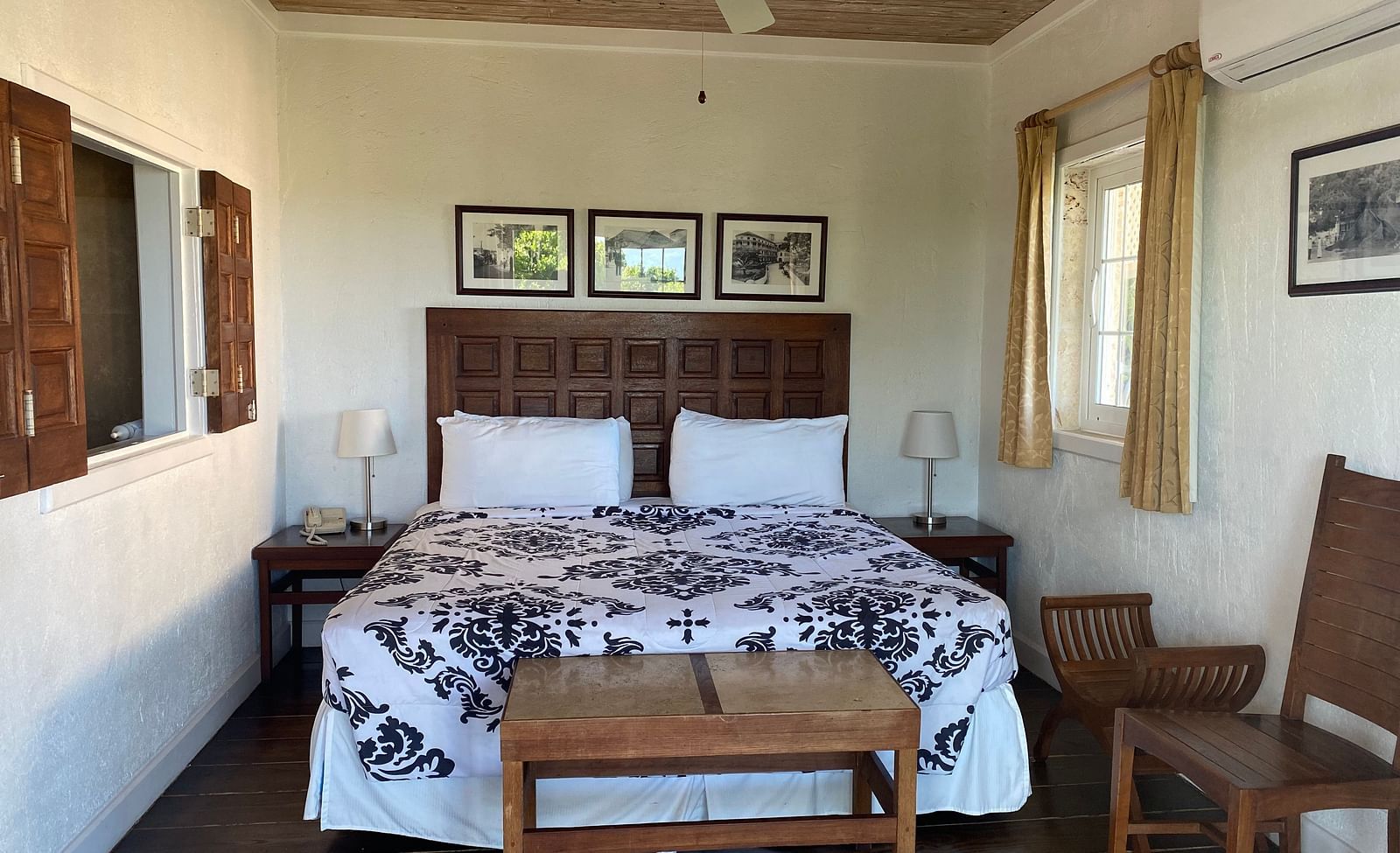Bedroom with a large bed, ceiling fan, table, chair, and framed art on the wall | A Stone's Throw Away