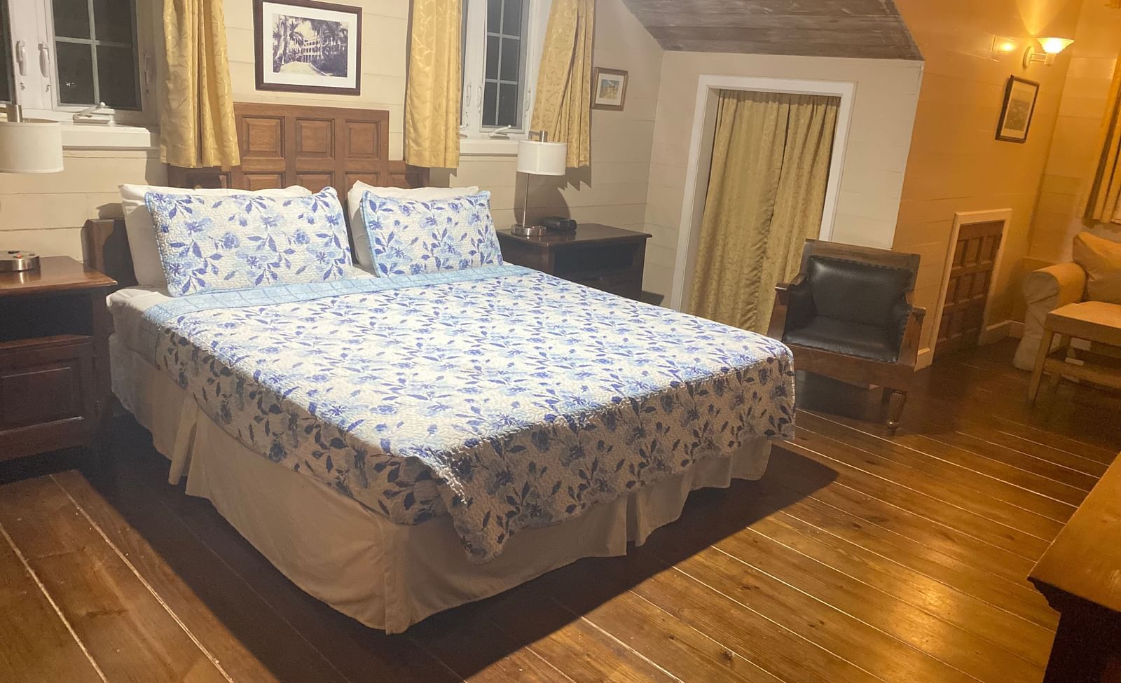 Bedroom with a bed, wooden floor, wooden furnishings, and beige walls | A Stone's Throw Away
