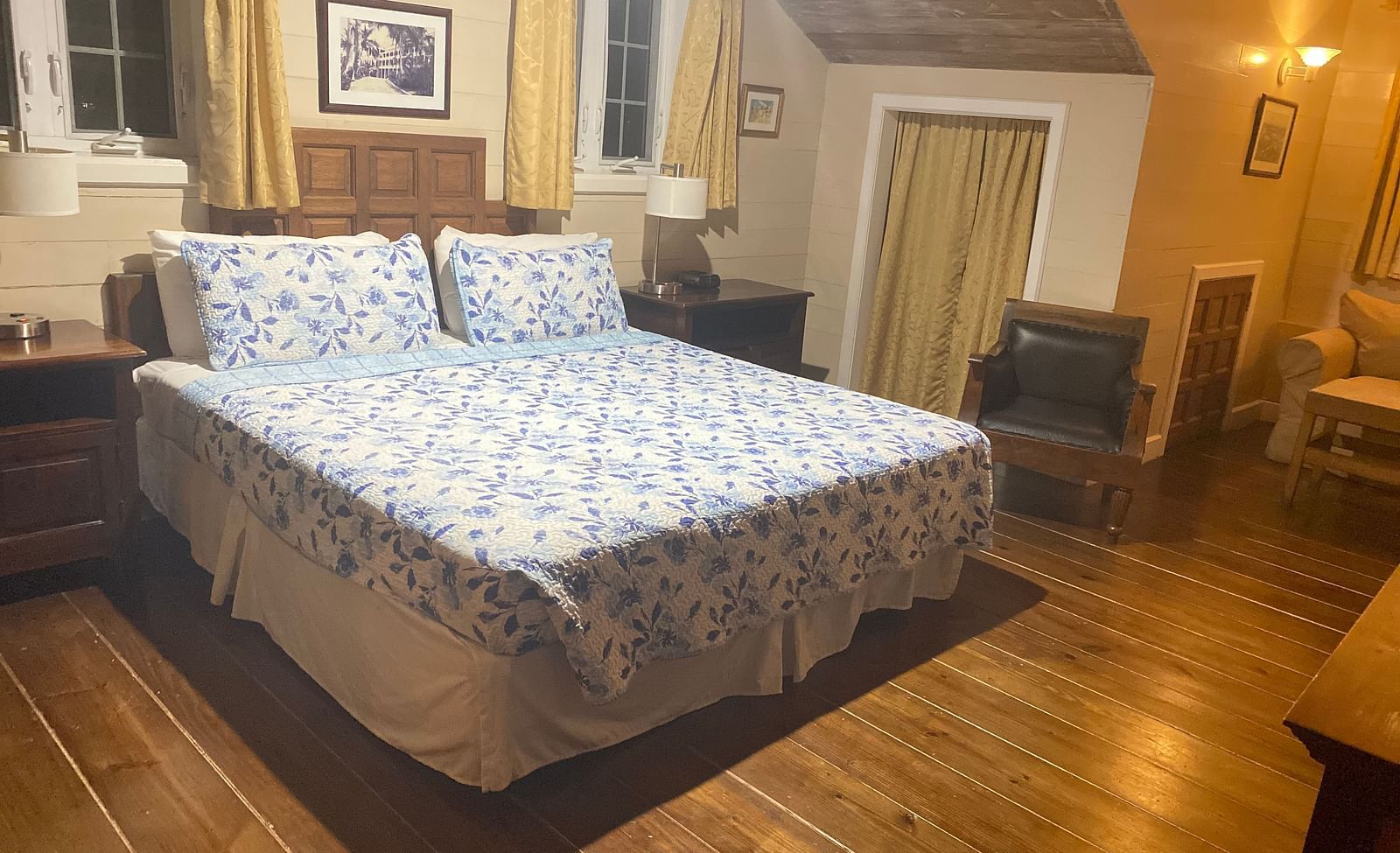 Bedroom with a bed, wooden floor, wooden furnishings, and beige walls | A Stone's Throw Away