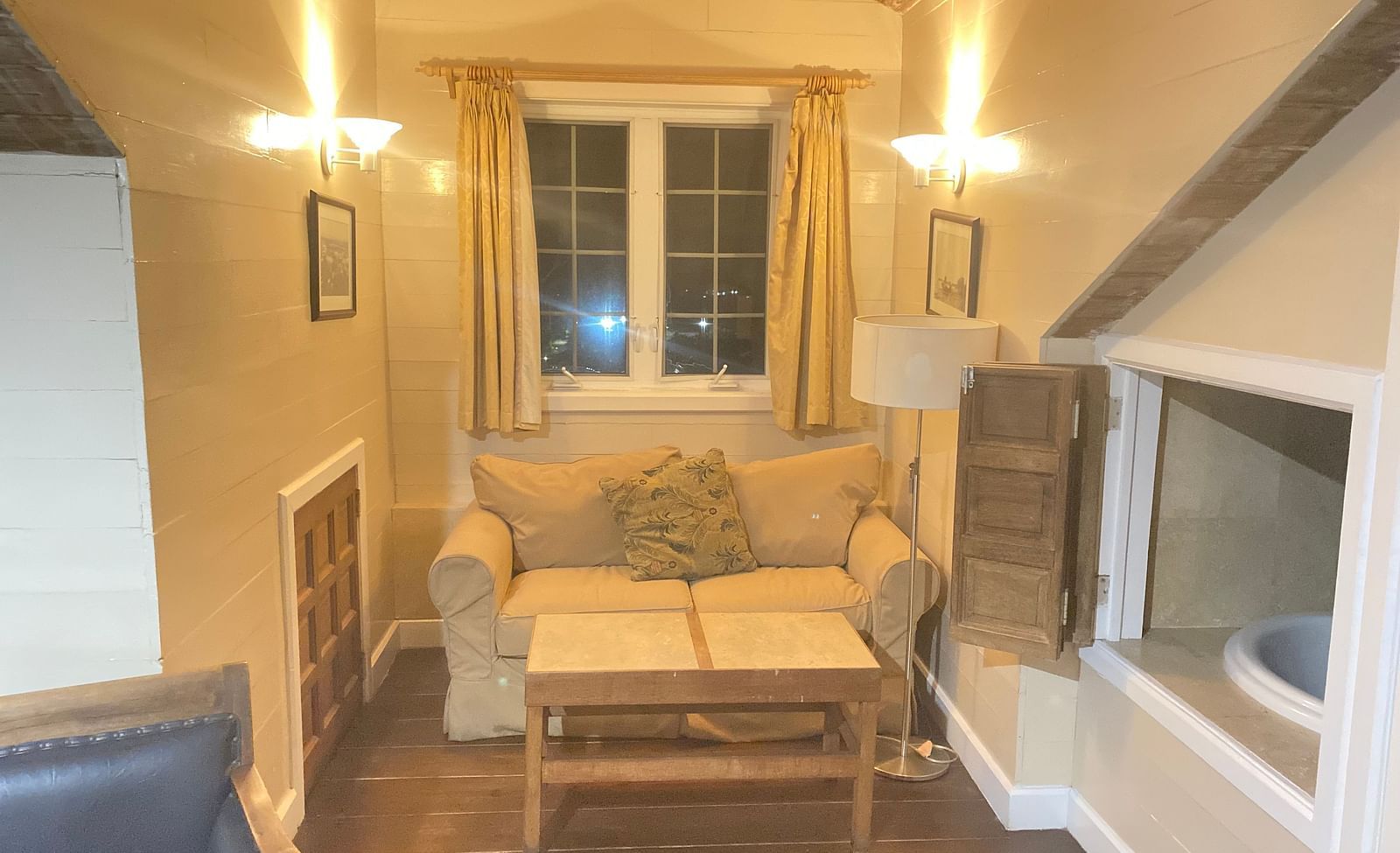 Cozy room with a sofa, a small table, and sloped wooden ceiling | A Stone's Throw Away