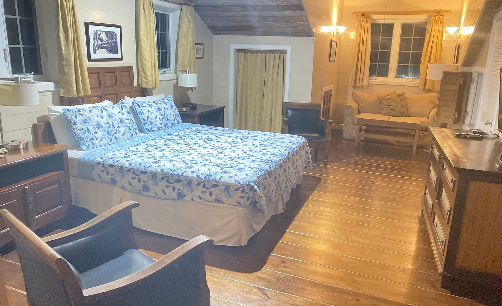 A warmly lit bedroom with a bed, wooden floor, wooden furniture, and beige walls | A Stone's Throw Away