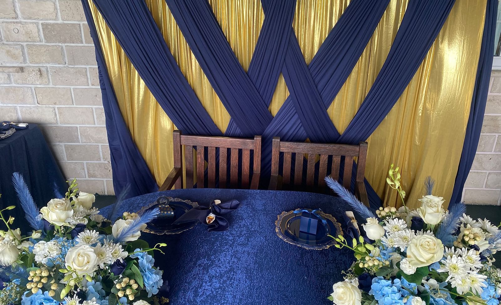 A table setup decorated with floral arrangements and a navy blue and gold backdrop | A Stone's Throw Away