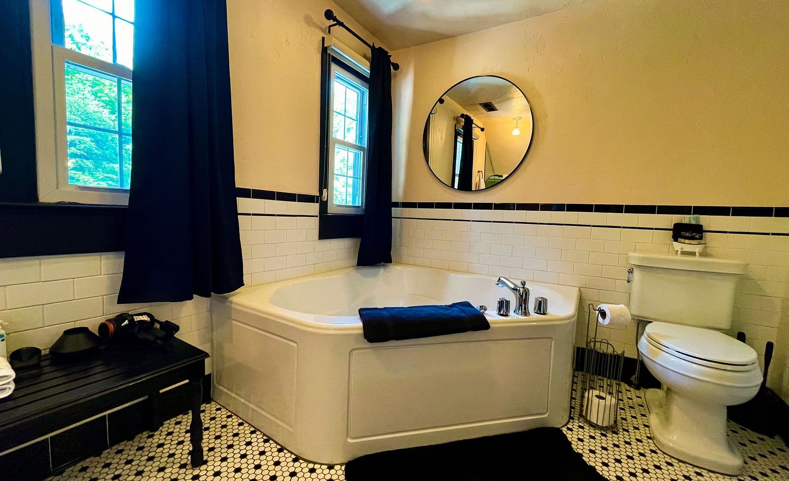 a modern bathroom featuring a bathtub along with a commode beside it and black curtains and doormat - Historic Tapoco Lodge