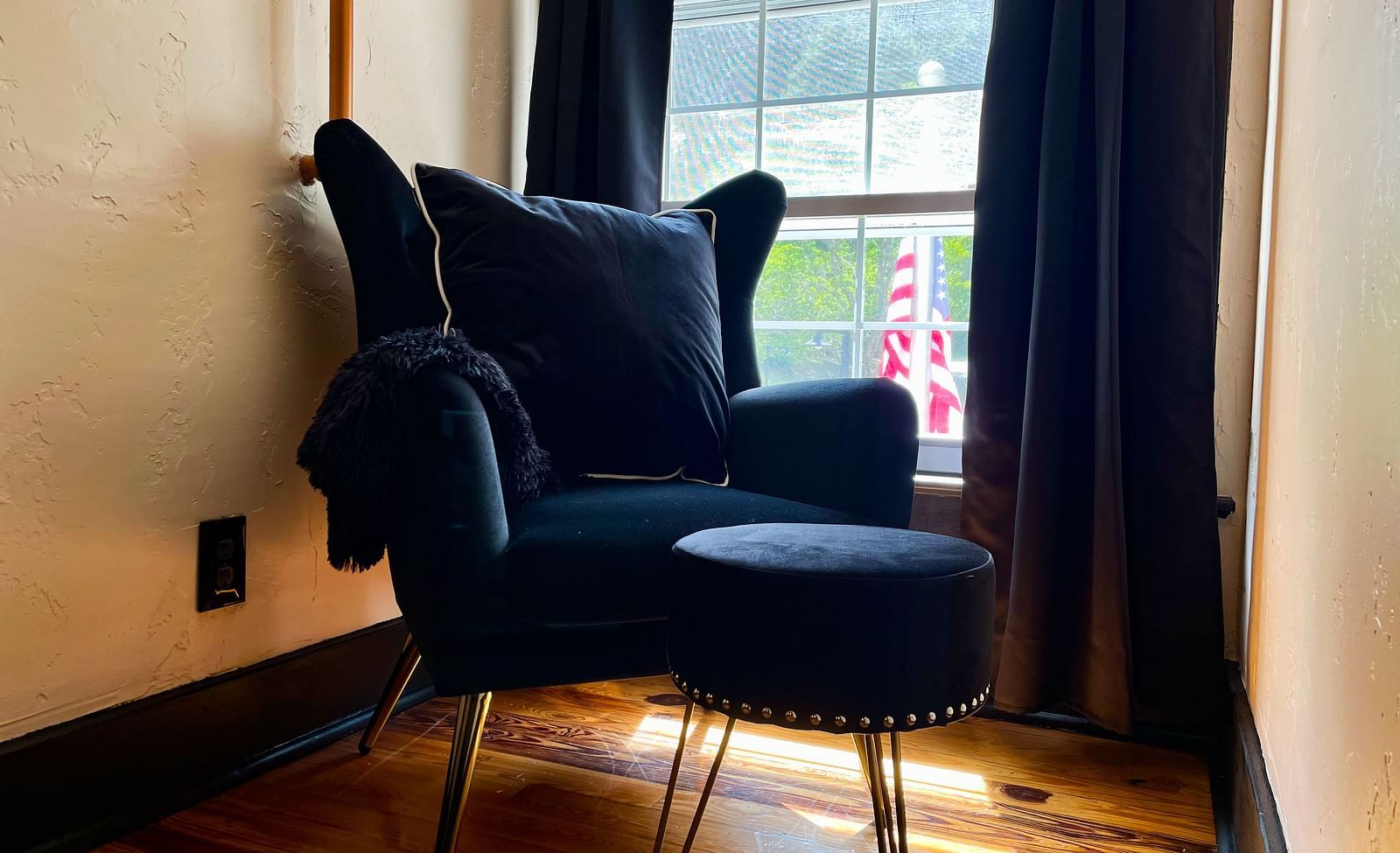 a close up shot of a clack colored cushioned armchair with a leg rest placed besidea a window with curtains - Historic Tapoco Lodge