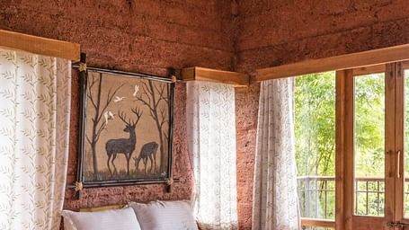 A bedroom with a wooden bed frame, tan walls, and a window with patterned curtains.