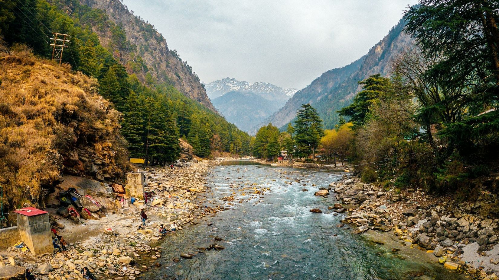 a shallow river with rocks on the bottom and clear water and mountains in the vicinity