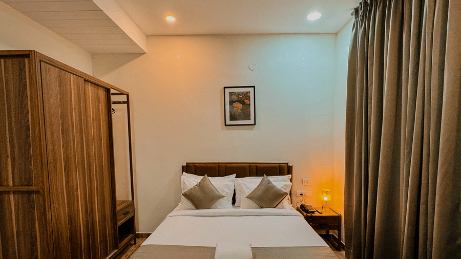 Furnishings including the queen size bed, a wooden wardrobe, and a bedside table seen in the bedroom of Coral 4BHK at Kove Smart Stays.