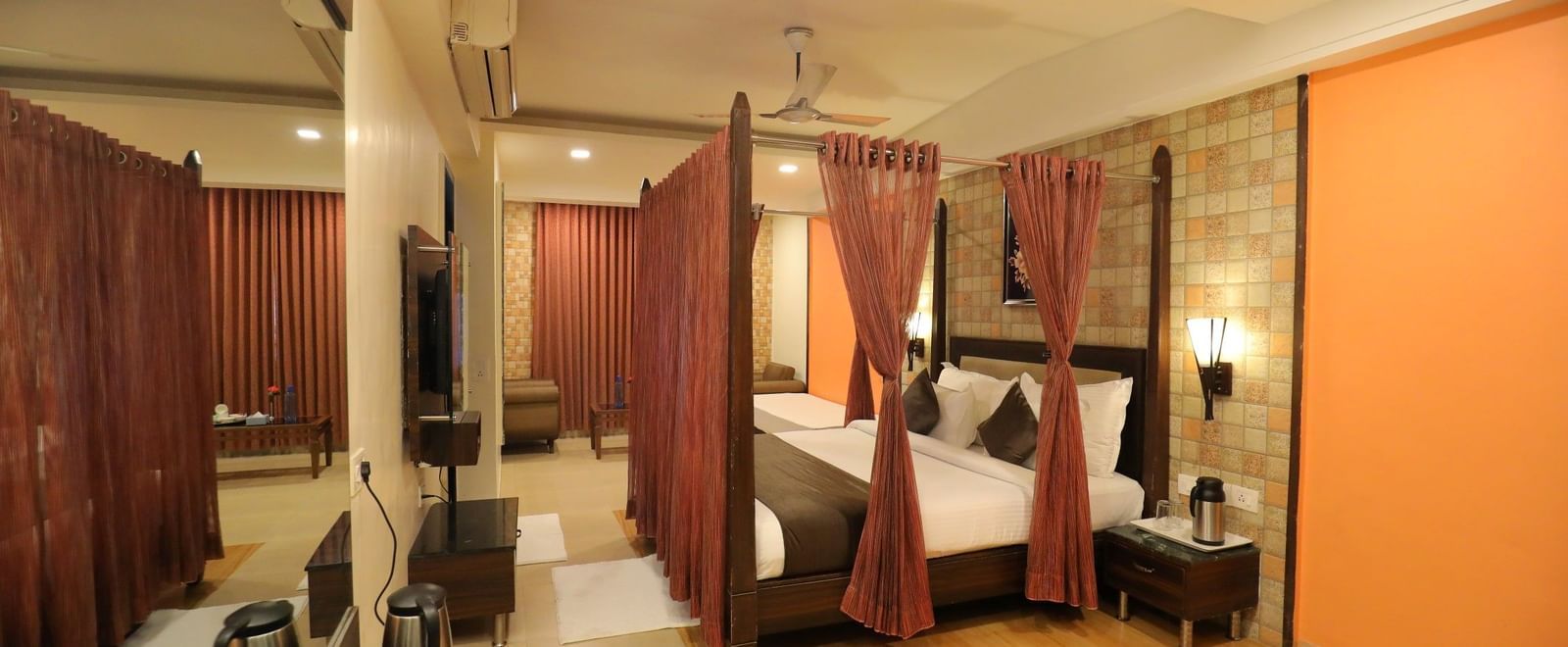 A spacious suite at Krushnai Resort with a four-poster bed, mirror, and a seating area.