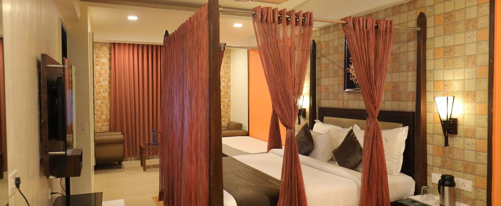 A wide view of a Krushnai Resort bedroom with a four-poster bed, dark wood furniture, and warm lighting.