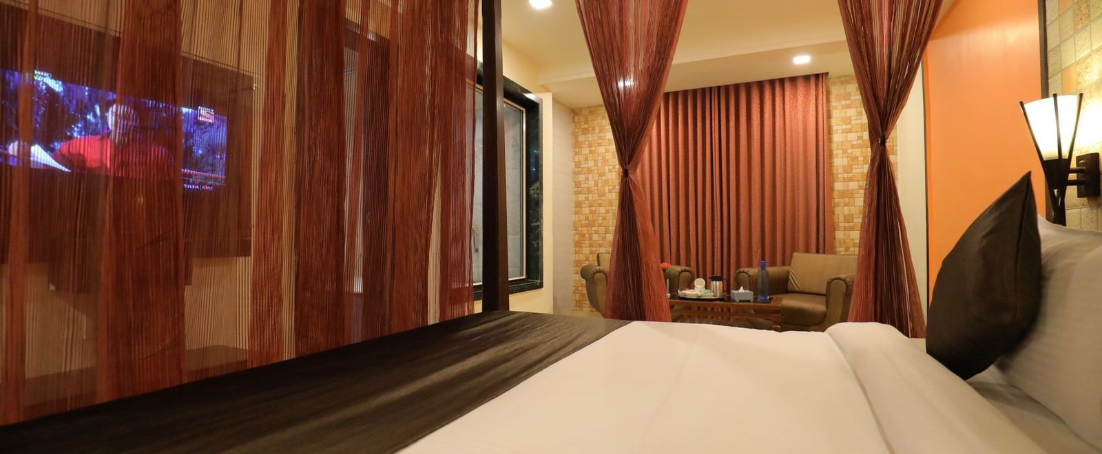 Honeymoon Suite at Krushnai Resort featuring a four-poster bed with red drapes and a flat-screen TV.