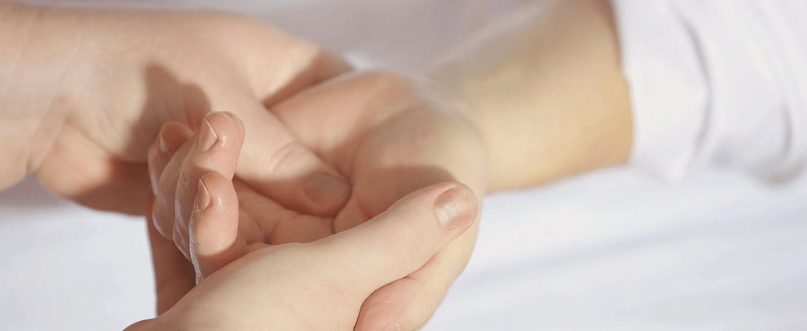 An image where you can see the palm of a person is getting treated by another person.