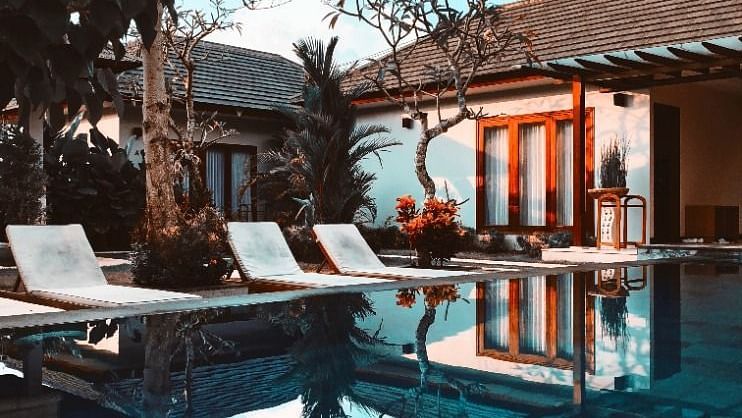a swimming pool view loungers next to it and a building in the background