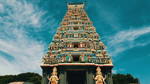 facade image of a temple with intricate carvings of deities on the roof