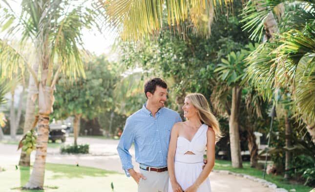 Couple walks down a garden pathway lined with palm trees, holding hands at Abaco Inn.