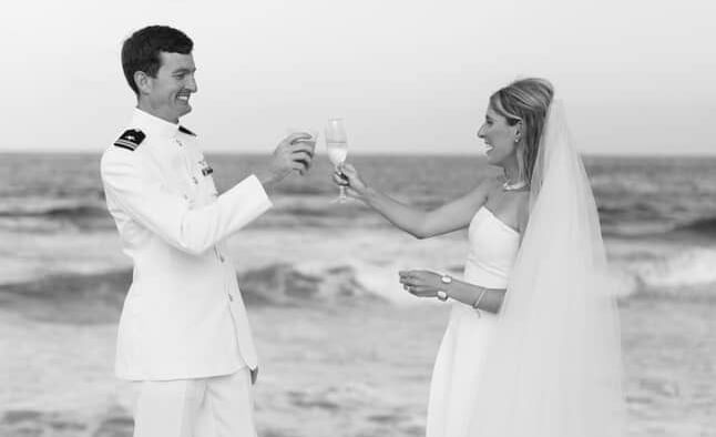 Two people exchange rings on beach during a wedding, guests in the background, Abaco Inn.