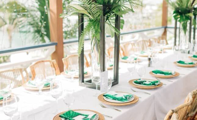 A corner view of a long table set with plates, glasses, and napkins under a wood canopy, Abaco Inn.