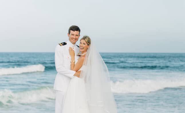 Two people in wedding attire standing on the sand near ocean, Abaco Inn.