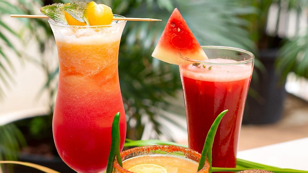 Three tropical cocktails with garnishes and an Aloha coaster at Hotel Mumbai House Mindspace, Malad.
