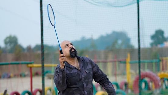 A man playing badminton at Themis Mudhouse - A Nature's Retreat Resort & Wellness