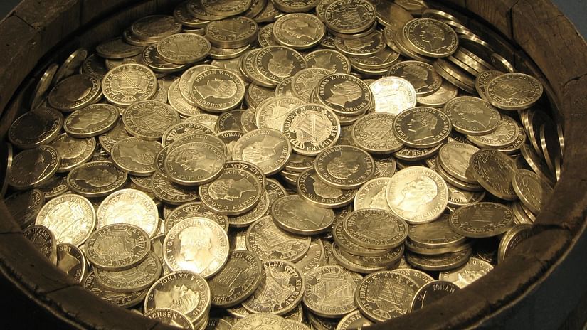 A close up of pot filled with coins with the light reflecting on top of it.