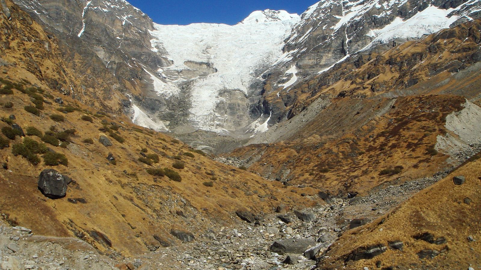 Rugged mountain landscape with a glacier and a waterfall.