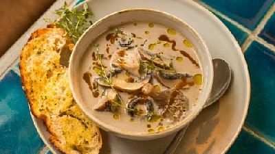 Bowl of soup with bread and a drink placed on a blue tiled table at Karma Chalets.