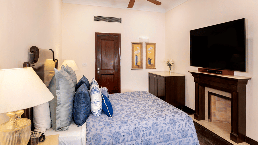 image of the Claridges Room awith a king size bed and a wall mounted TV above the fireplace at The Claridges Nabha Residence